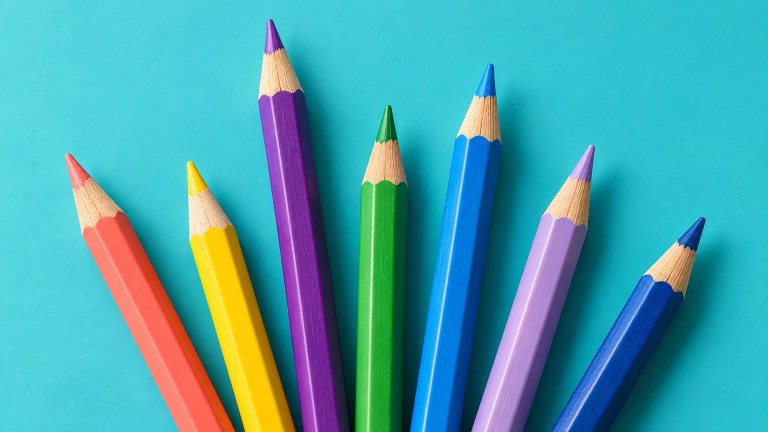 Colourful wooden pencils of different lengths on a turquoise surface.